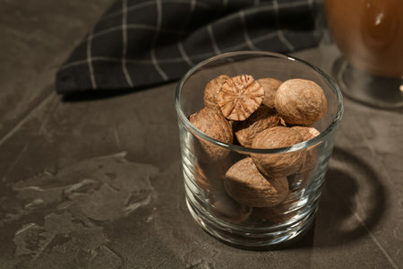 Nutmegs in glass on black table. Space for textの写真素材