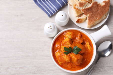Bowl of delicious chicken curry on white wooden table, flat lay. Space for textの写真素材