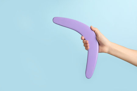 Woman holding boomerang on light blue background, closeup. Space for textの写真素材