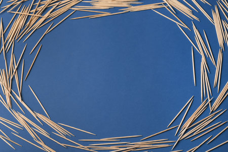 Frame of wooden toothpicks on blue background, flat lay. Space for textの写真素材