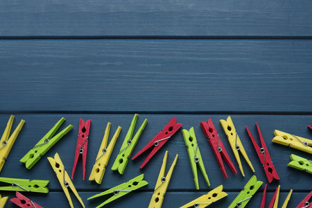 Colorful plastic clothes pins on blue wooden background, flat lay. Space for textの写真素材