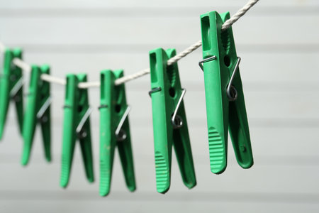 Green plastic clothespins on rope against light background, closeupの写真素材