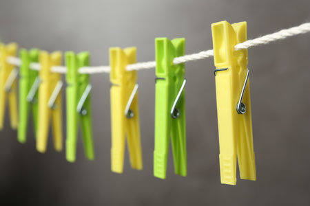 Colorful plastic clothespins on rope against gray background, closeupの写真素材