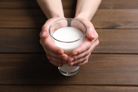 Woman holding glass of milk at wooden table, closeupの写真素材