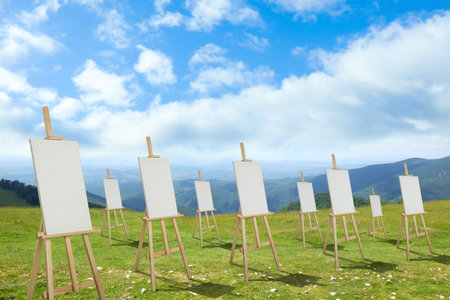 Wooden easels with blank canvases in mountains on sunny dayの写真素材
