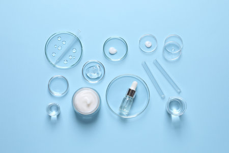 Laboratory glassware and natural ingredients for organic cosmetic product on light blue background, flat layの写真素材