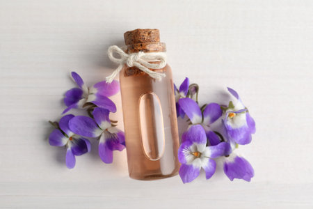 Beautiful wild violets and essential oil on white wooden table, flat lay. spring flowersの写真素材
