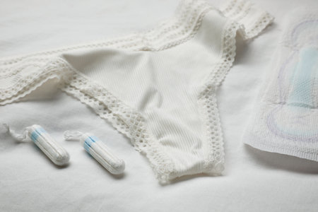 Woman's panties, menstrual pad and tampons on white fabricの写真素材