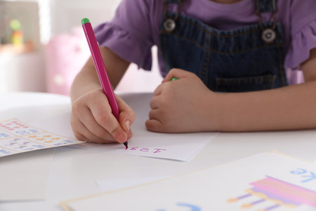 Little girl writing numbers in classroom at English lesson, closeupの写真素材