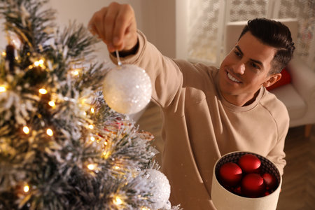 Handsome man decorating Christmas tree at home, above viewの写真素材