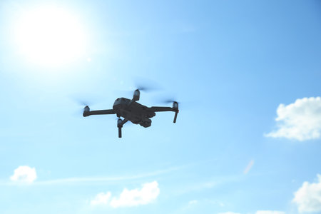 Modern drone with camera flying in the sky on sunny day