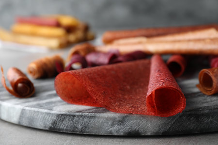 Delicious fruit leather rolls on gray table, closeupの写真素材