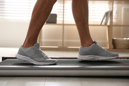 Sporty man training on walking treadmill at home, closeupの写真素材