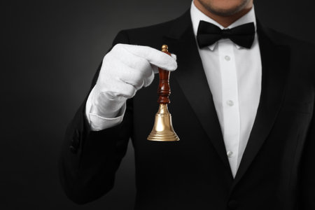Butler holding hand bell on black background, closeupの写真素材