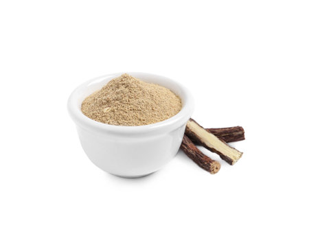 Powder in bowl and dried sticks of liquorice root on white backgroundの写真素材