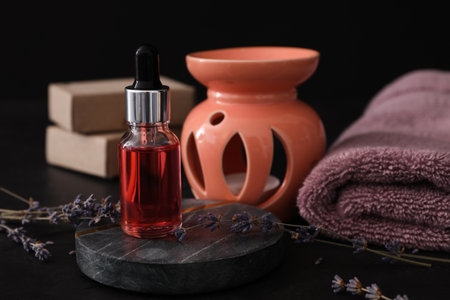Lavender essential oil for aroma lamp on black tableの写真素材