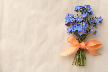 Beautiful blue forget-me-not flowers tied with ribbon on light background, top view. Space for textの写真素材