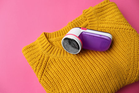 Modern fabric shaver and woolen sweater on pink background, top viewの写真素材