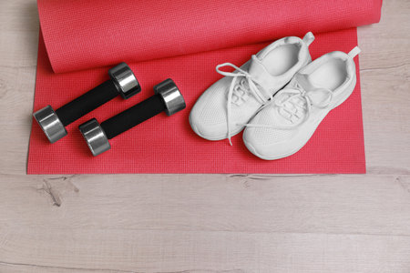 Dumbbells, sneakers and mat on wooden floor, above viewの写真素材
