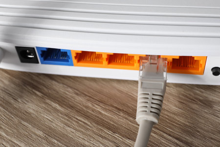 Connected cable to router on wooden table, closeup. wireless internet communication