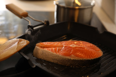 Frying pan with fresh salmon steak on stoveの写真素材