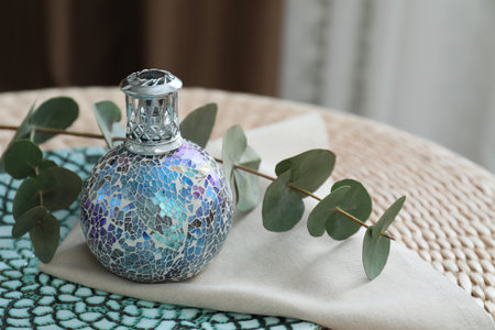 Stylish catalytic lamp with eucalyptus branch on wicker stand indoors. Cozy interiorの写真素材