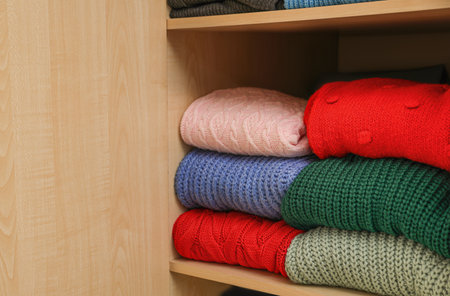 Different folded warm sweaters on wooden shelfの写真素材