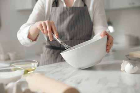 Woman making dough at table in kitchen, closeupの写真素材