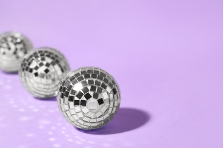 Shiny disco balls on lilac background. Space for textの写真素材