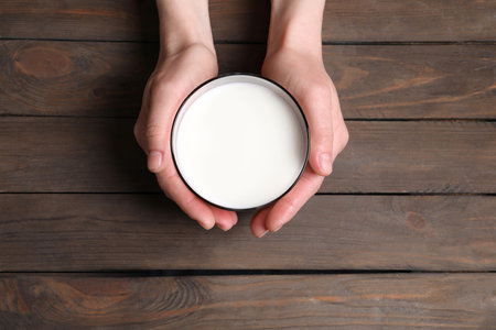 Woman holding glass of milk at wooden table, top viewの写真素材