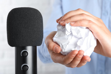 Woman making ASMR sounds with microphone and crumpled paper, closeupの写真素材