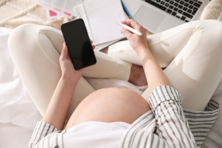 Pregnant woman working on bed at home, above view. Maternity leaveの写真素材