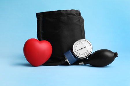 Blood pressure meter and toy heart on light blue backgroundの写真素材