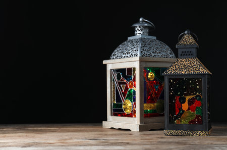Decorative Arabic lanterns on wooden table against black background, space for textの写真素材