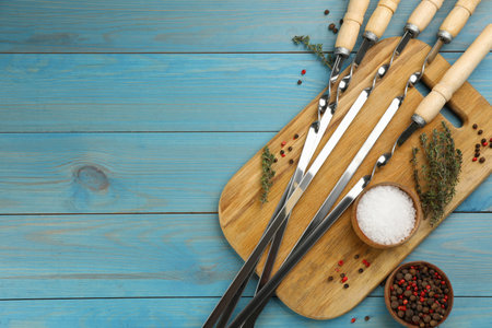 Flat lay composition with metal skewers on light blue wooden table. Space for textの写真素材