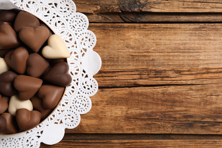 Delicious heart shaped chocolate candies on wooden table, top view. Space for textの写真素材