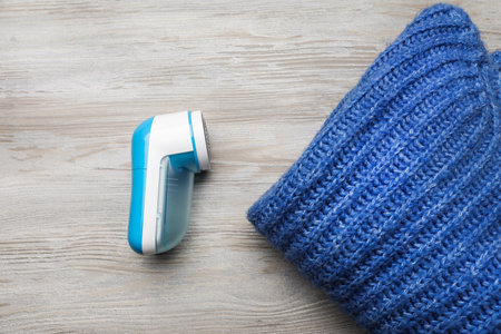 Modern fabric shaver for lint removing and sweater on wooden table, flat layの写真素材