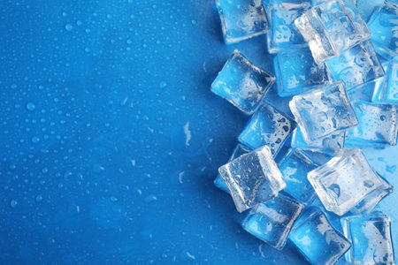 Ice cubes with water drops on light blue background, flat lay. Space for textの写真素材