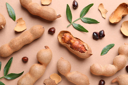 Ripe tamarinds and fresh leaves on beige background, flat layの写真素材