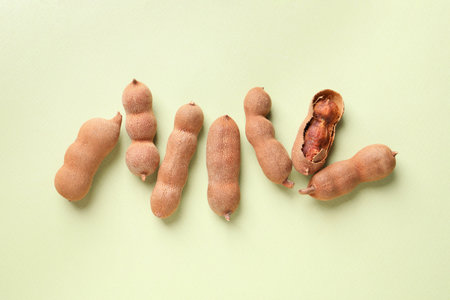 Ripe tamarinds on light green background, flat layの写真素材