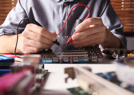 Technician repairing electronic circuit board at table, closeupの写真素材