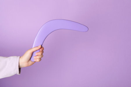 Woman holding boomerang on lilac background, closeupの写真素材