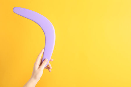 Woman holding boomerang on yellow background, closeup. Space for textの写真素材