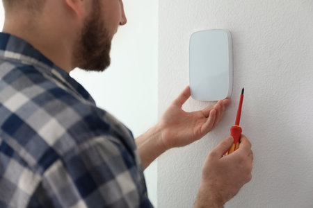 Man installing security alarm system on light wall at home, closeupの写真素材
