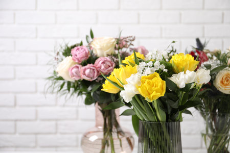 Beautiful bouquets with fresh flowers against white brick wall, closeup. Space for textの写真素材