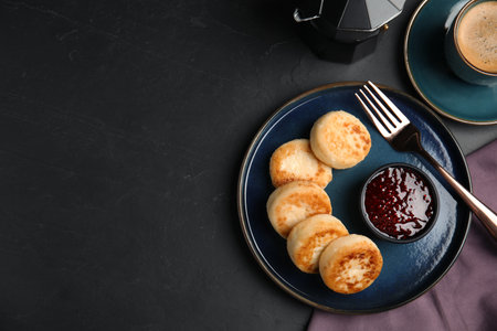 Delicious cottage cheese pancakes with jam on black table, flat lay. Space for textの写真素材