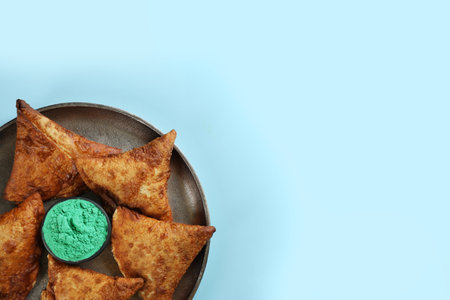 Top view of traditional Indian food and color powder dye on turquoise background, space for text....