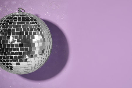 Bright shiny disco ball on violet background, top view. Space for textの写真素材