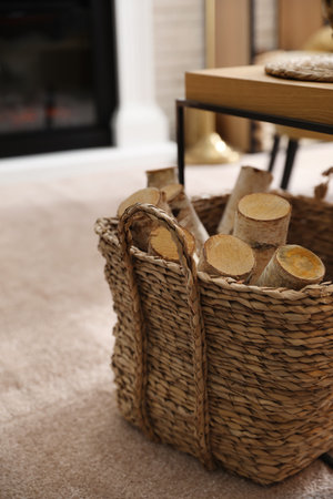 Firewood in wicker basket in room, closeup viewの写真素材
