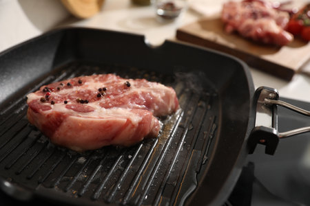 Frying pan with fresh raw meat on stoveの写真素材